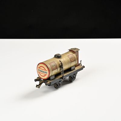 un vieux wagon de train miniature posé sur une surface blanche, sur fond noir