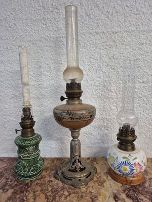 Trois lampes à huile anciennes sont posées sur un plan de travail en marbre