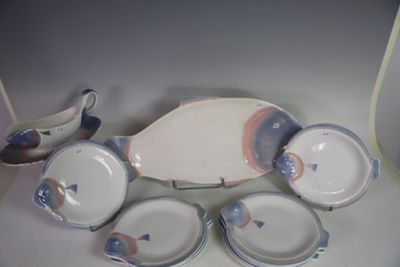 une assiette blanche ornée d'un motif de poisson, à côté de bols et de cuillères