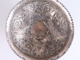 a silver bowl with a design on it on a white surface