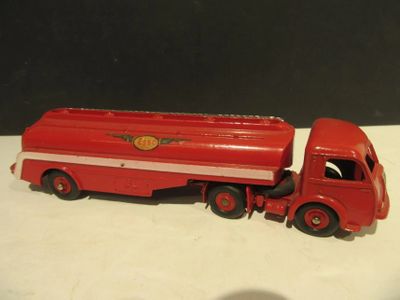 un camion jouet rouge posé sur une surface blanche