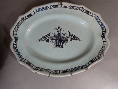 une assiette bleue et blanche sur laquelle est représenté un vase