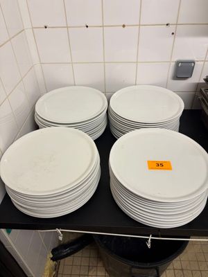 Plusieurs assiettes blanches sont empilées sur une étagère noire dans une cuisine