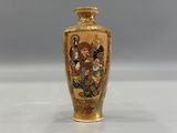 a gold vase with a picture on it on a white surface