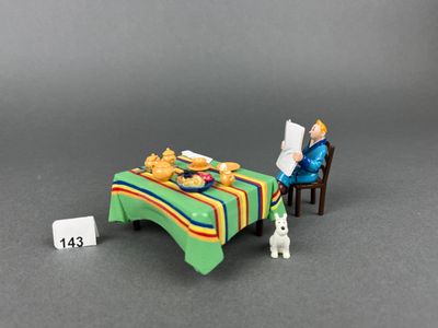 a small doll sitting at a table with a plate of food on it
