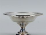 un bol ancien en argent, muni d'un pied et posé sur un socle, sur fond blanc