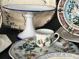 many plates and cups sitting on a table with a cake stand