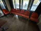 several orange chairs are lined up in a row in front of a window