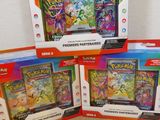 trois boîtes de cartes Pokémon posées sur une table en bois