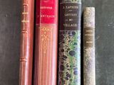 Plusieurs livres sont alignés sur une table devant un fond noir.
