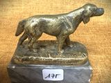 statue en bronze représentant un chien, posée sur un socle en marbre sur lequel est fixée une étiquette