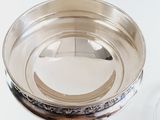 a silver bowl on a stand next to a glass of wine