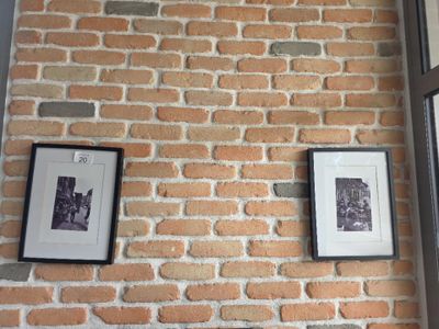 deux photos encadrées accrochées à un mur de briques près d'une fenêtre