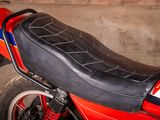 a red motorcycle with a black seat in a garage
