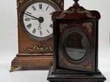 two clocks sitting next to each other on a white surface