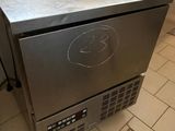 a small stainless steel refrigerator sitting on a tiled floor