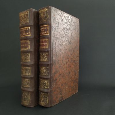 two old books are sitting side by side on a black surface