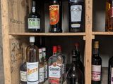 many bottles of alcohol sitting on a wooden shelf