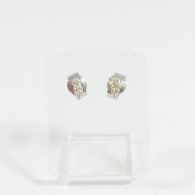 une paire de boucles d'oreilles en argent posée sur un présentoir transparent