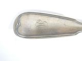 a silver spoon with a monogram on it on a white surface