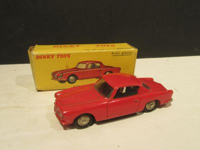 une petite voiture rouge posée devant une boîte