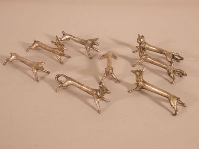 six silver dog figurines on a white surface