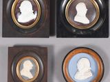 four framed portraits of men and women are displayed in wooden frames