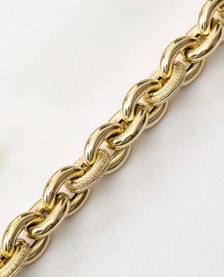 a close up of a gold chain bracelet on a white surface