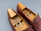une paire de chaussures en cuir rouge à semelles en bois posées sur une surface grise