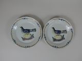 two plates with birds painted on them on a table