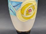 a white vase with a yellow rose on the side of it