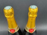 two bottles of champagne sitting next to each other on a table