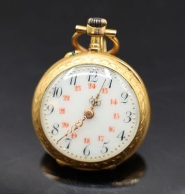 gros plan d'une montre de poche en or sur une surface noire
