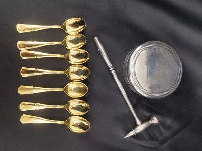 a lot of gold spoons and a silver spoon on a black cloth
