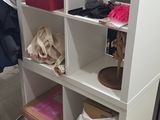 une bibliothèque blanche sur laquelle sont posés de nombreux objets, dans une pièce