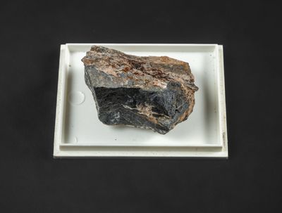 un caillou posé sur une assiette blanche, sur une table noire