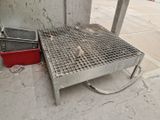 une grille métallique posée par terre à côté d'un seau rouge