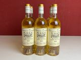 trois bouteilles de vin posées sur une table près d'un mur rouge