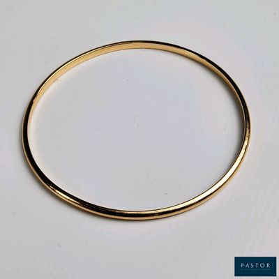 gros plan d'un bracelet en or sur une surface blanche
