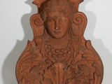 une photo d'une sculpture en argile représentant le visage d'une femme, posée sur une étagère