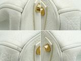 four pictures of a white purse with gold handles and a zipper