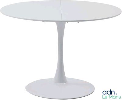 La table est blanche et possède un piètement circulaire.