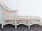 a white wicker chaise sitting on a black floor