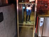 une personne se tenant dans un ascenseur, avec une pancarte accrochée à la porte