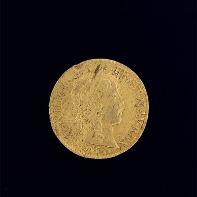 une vieille pièce d'or posée sur une surface noire, avec un fond noir
