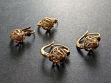 trois bagues en or et une paire de boucles d'oreilles posées sur un fond noir