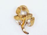 un gros plan d'une broche en forme de fleur ornée de perles sur un fond blanc
