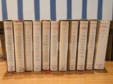 several books are lined up on a table in front of a blue and white striped wall