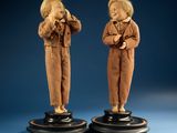 pair of wooden figurines of a boy and a girl on pedestals