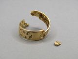 un gros plan d'une bague en or posée sur une table, à côté d'un petit morceau d'or